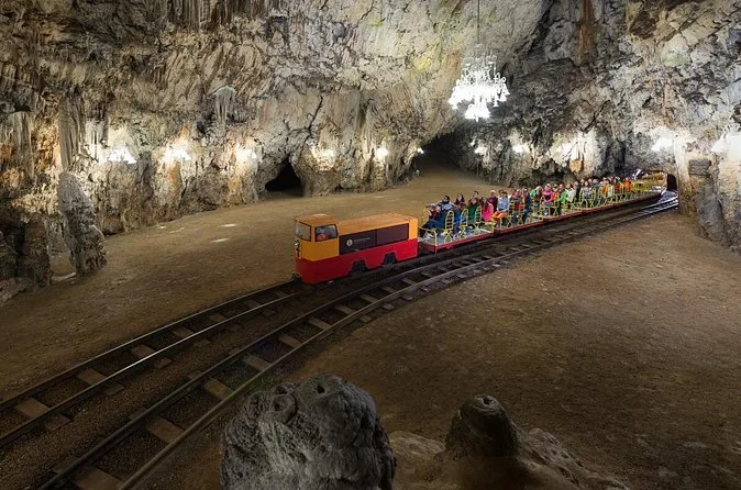 Die Höhlenbahn fährt durch eine weite, beleuchtete Halle in der Höhle von Postojna